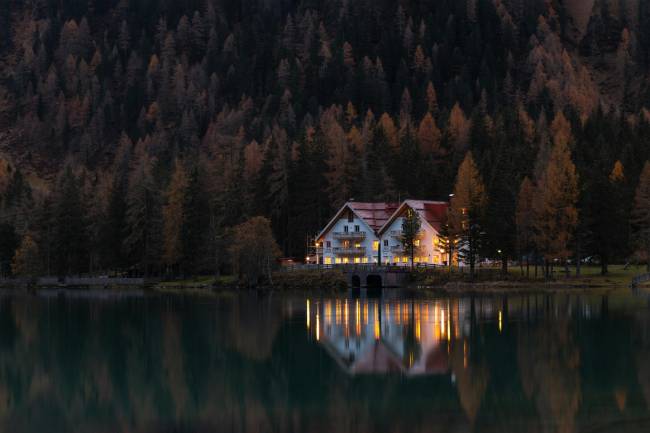 A home by the lake and surrounded by forest lit in the evening