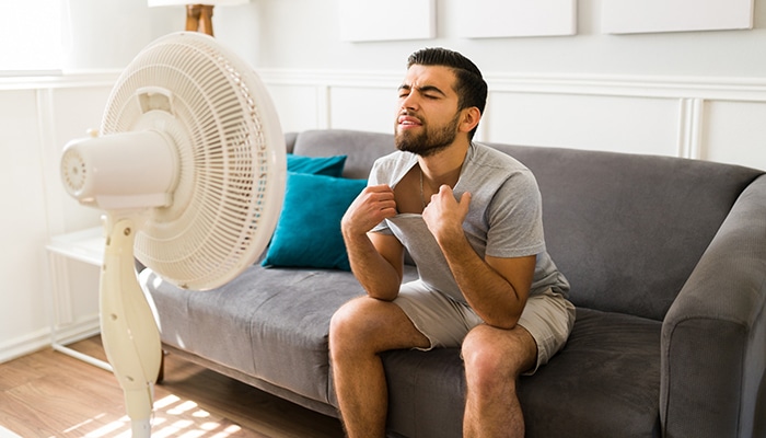 Man sitting on couch in front of fan